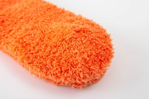 Close-up of soft orange coral fleece texture on thick warm winter lounge socks