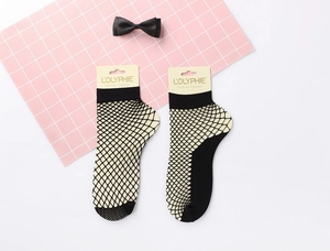 Detail of black fishnet ankle socks with wide elastic cuffs and brand tag on pink grid