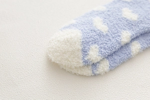 Detail of light blue coral fleece socks with white polka dots and thick plush texture