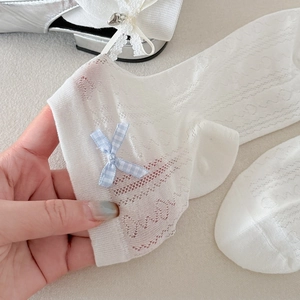 Détail de chaussettes en dentelle blanche ornées d'un joli nœud à carreaux bleu clair