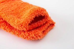 Macro view of soft orange coral fleece texture and warm thick knitted socks fabric
