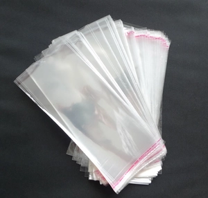 Close-up of clear OPP self-adhesive packaging bags for socks stacked on a textured grey surface