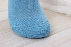 Detailed macro view of the reinforced toe seam on light blue cotton low-cut socks