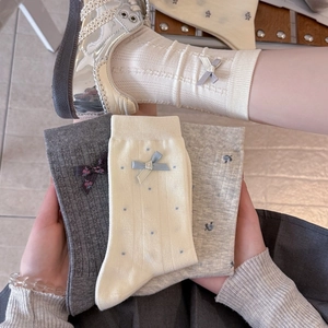 Detail of cotton socks showing floral embroidery and delicate 3D bow accents