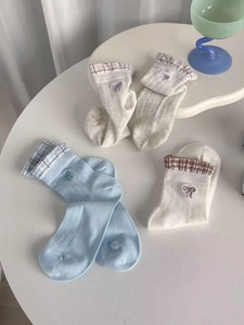 Detail of sheer mesh socks featuring embroidered bows and plaid cuffs in blue and grey