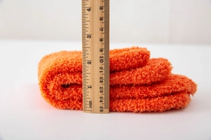 Close-up of thick orange coral fleece fabric showing 3-inch thickness for winter socks