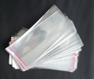 Stack of transparent self-adhesive OPP packaging bags with red sealing strips for socks