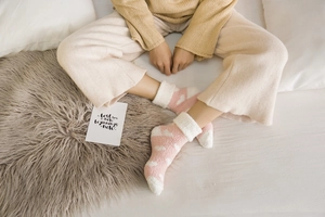 Detail of pink coral fleece socks with cloud pattern and thick white plush cuffs