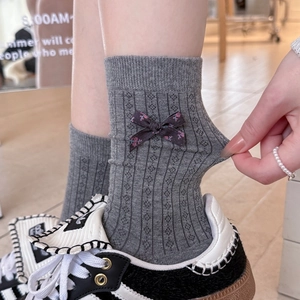 Close-up of grey ribbed cotton crew socks featuring a floral bow and vintage sneakers