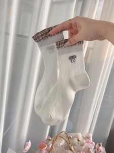 Detail of white mesh socks with brown plaid trim and delicate bow embroidery details
