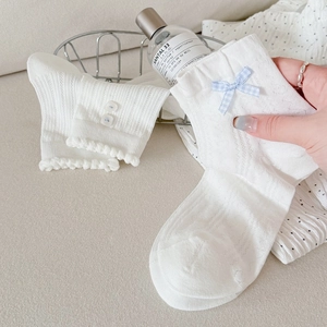 Gros plan de chaussettes en dentelle blanche avec nœud à carreaux et détails de volants