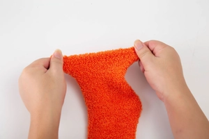 Detail of orange coral fleece sock showing elastic stretch and soft fuzzy texture