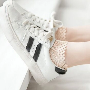 Detail of floral lace edge low-cut socks in beige paired with classic white sneakers