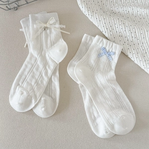 Détail de chaussettes en résille blanche avec nœuds en dentelle et pendentifs cœur
