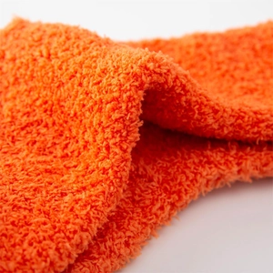 Close-up of fluffy orange coral fleece fabric texture showing soft plush warm material