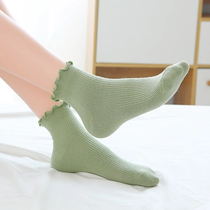 Detail of light green ribbed cotton socks with elegant ruffled cuffs for women