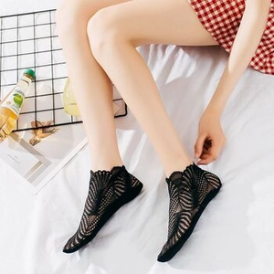 Detailed view of women's black lace mesh socks with scalloped edges worn by a model