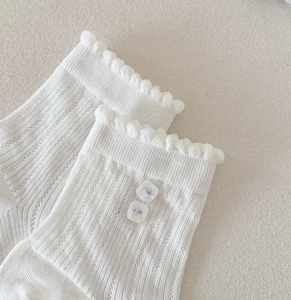 Gros plan de chaussettes en dentelle blanche avec bords à volants et boutons carrés