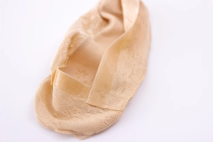 Detail of beige lace no-show socks with non-slip silicone strips on a white background