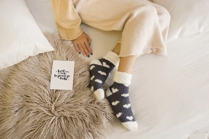 Detailed view of warm gray coral fleece socks with white heart patterns and fuzzy cuffs