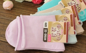 Detail of colorful non-slip socks in pastel colors with loose comfort cuffs on wood