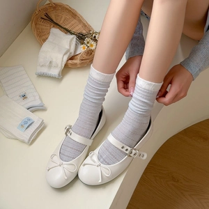 Close-up of blue striped mesh socks with white Mary Jane shoes in a soft aesthetic