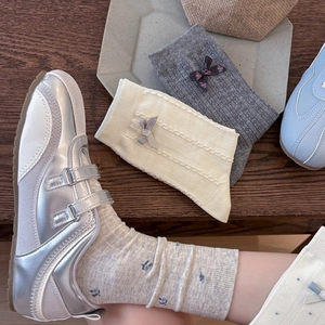 Detailed view of grey floral knit and cream bow cotton socks paired with silver sneakers