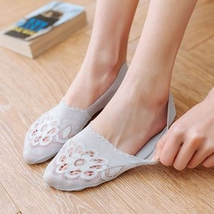 Close-up of light grey lace no-show socks with floral embroidery on wooden floor