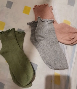 Close-up of pink, grey and green ribbed knit socks with elegant ruffled lace cuffs