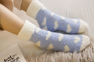 Close-up of thick light blue coral fleece socks with white heart patterns and plush texture