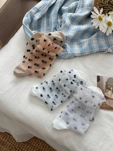 Close-up of three pairs of sheer glass silk socks with red hearts and ruffled edges