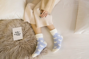Detail of blue coral fleece warm socks with white hearts and fuzzy cuffs in a cozy setting