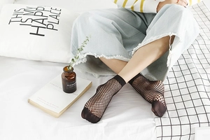 Close-up of black fishnet socks featuring fine mesh weaving and reinforced toe detail