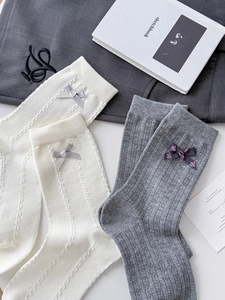 Detailed knit patterns and bow accents on high-quality white and grey cotton crew socks