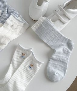 Close-up of cute light blue mesh socks set with lace bow and bear embroidery