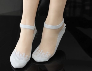 Detail of white lace invisible boat socks with floral embroidery on sheer mesh fabric