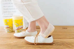 Detailed side view of beige lace invisible boat socks for women on light wooden floor