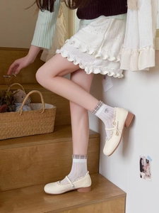 Detail of sheer mesh socks with brown plaid trim and delicate floral embroidery
