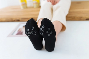 Detail of black low-cut socks featuring anti-slip floral silicone grip on the sole