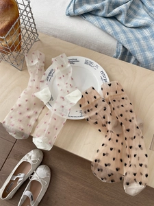 Detail of sheer tulle socks featuring heart and polka dot patterns on a light wooden table