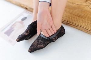 Detail of black lace no-show socks with anti-slip grip on sole worn by model