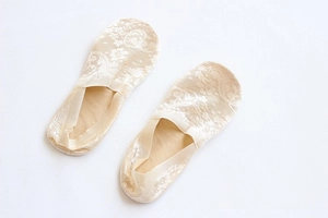 Detailed view of beige lace boat socks with floral crochet pattern and non-slip sole