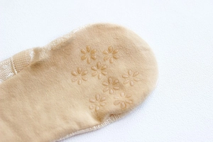 Detail of floral anti-slip silicone pattern on the bottom of beige low cut boat socks
