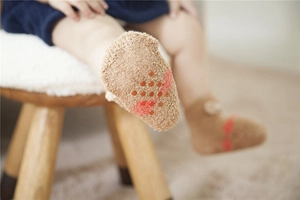 Detail of baby coral fleece floor socks with red anti-slip silicone dots and cute bow