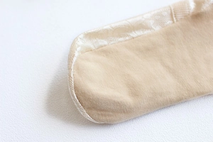 Macro detail of fine knit bamboo fiber socks with smooth beige silk edge stitching