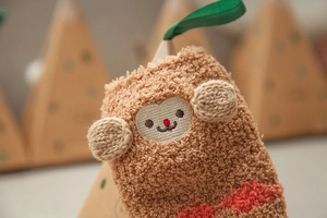 Close-up of coral fleece kids sock with cartoon embroidery and 3D ears in gift box