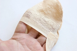 Detailed view of breathable skin-tone lace fabric showing thin texture and elastic mesh