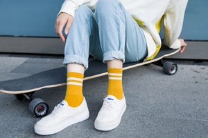 Detalle de calcetines amarillos de algodón con rayas blancas sobre un longboard