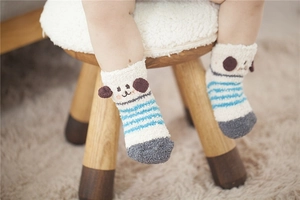Close-up of baby warm coral fleece socks with 3D cartoon dog ears on wooden stool
