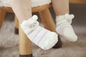 Close-up of white plush baby socks with purple stripes and cute sheep embroidery
